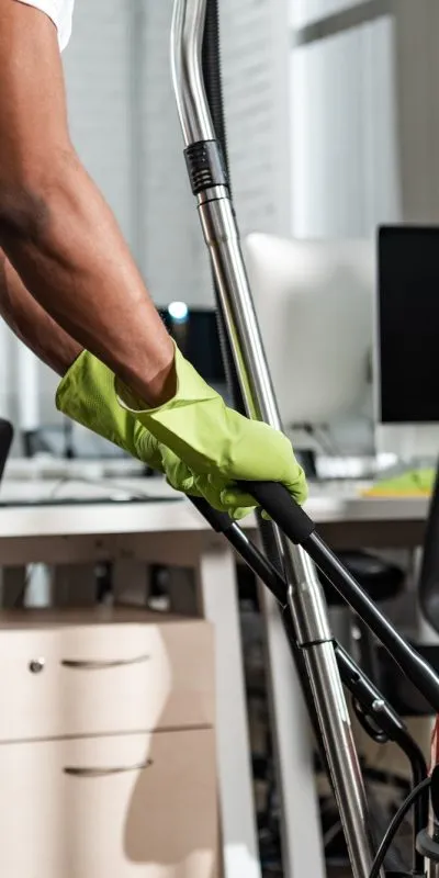 cropped view of african american cleaner moving vacuum cleaner in office